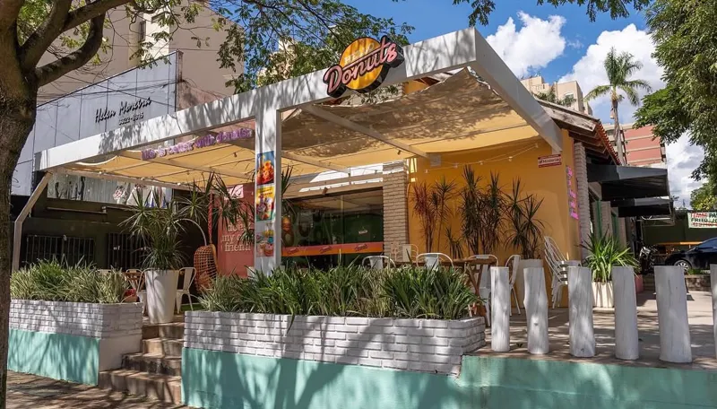 Fachada da Hello Donuts em Londrina: varanda com pergolado branco, paredes amarelas e o letreiro redondo da marca